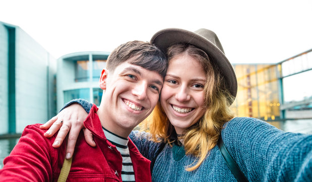 Happy boyfriend and girlfriend in love having genuine fun taking selfie at modern area in Berlin - Teenagers life style and travel concept with young millenial tourist around the city - Vivid filter