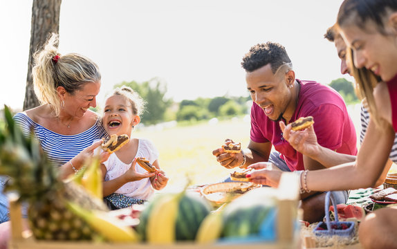 Cropped view of happy multiracial families having fun with kids at pic nic barbecue party - Multiethnic love concept with mixed race people eating with children at public park - Warm vivid filter