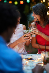 young adults making a toast, drinking cocktails, laughing. Fun, socializing, conversation concept