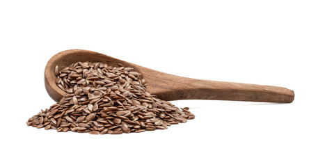 Side view of linseeds or flax seed on a tilted brown wooden spoon with spill and isolated on white background