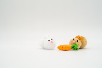 Two cute brown and white rabbit pom pom toys with carrot isolate
