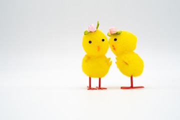 Two yellow easter chick pom pom toys with rose hats whispering o