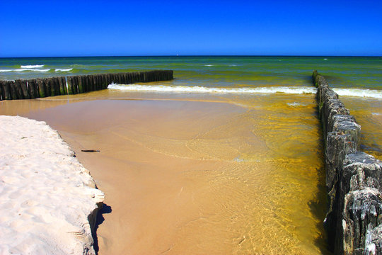 Colorful seascape of the Baltic Sea seashore and sandy beach in town of Karwia, north Poland, with remaining of wooden breakwater constructions