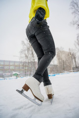 Figure skating on the street at an outdoor ice rink. Close-up of the skater's legs on ice. A woman goes in for sports.