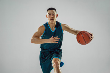 Fototapeta premium Young basketball player of team wearing sportwear training, practicing in action, motion in run isolated on white background. Concept of sport, movement, energy and dynamic, healthy lifestyle.