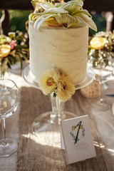 cake with white cream, decorated with lilies, asters and lemon slices