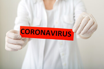 Coronavirus, red warning sign with the text Coronavirus in doctor hands in white coat and gloves....