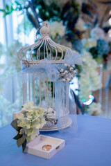 wedding rings in a box decorated with flowers, decorative birdcage, floral decor in the background
