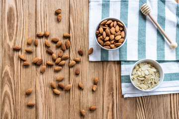 Fototapeta premium nuts in bowl on a wooden background. Rustic style. Almonds on a towel. Vegetarian food.