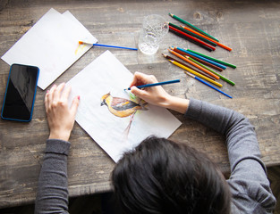 a young girl draws with watercolor pencils