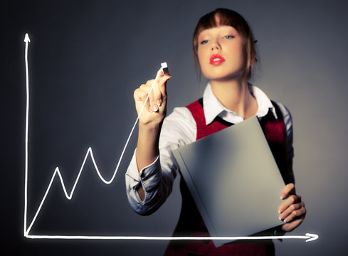 Young pretty businesswoman woman draws a graph on an invisible screen assesses the risks and success of her business. Concept guarantee of success and economic calculations. Advertising space