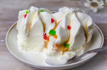 Close-up ice cream sundae with colored fruit slices on a white plate .