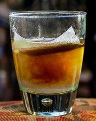 A tea bag infused in a transparent glass of hot water releases its precious content