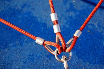 High angle closeup shot of three red ropes attached to a metal holder with a blue background