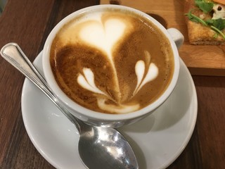 cup of coffee with cream on wooden background