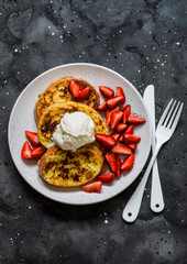 Baked french toast with fresh strawberries and ice cream on a dark background, top view