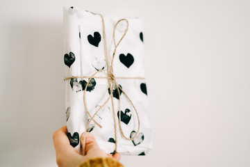 a gift in a woman's hand wrapped in homemade wrapping paper with black hearts for Valentine's day