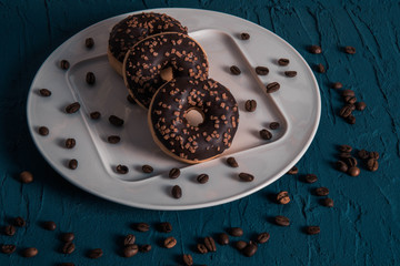 sprinkled coffee grains and chocolate donuts lie on a plate