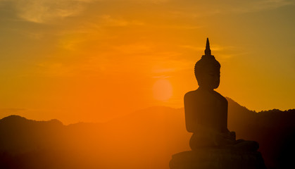 Silhouette  Buddha on a sunset background shining from behind