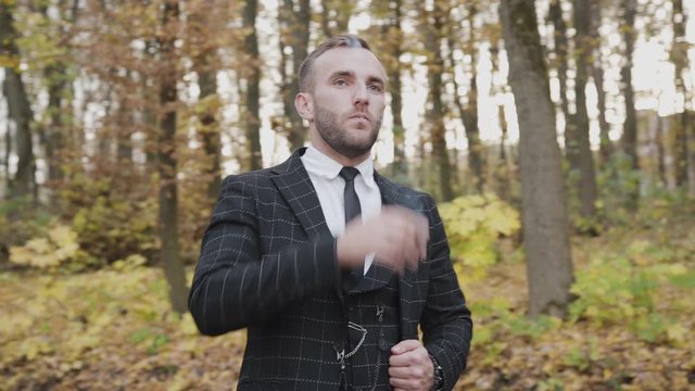 Portrait of handsome gentleman smoking a cigar in autumn forest