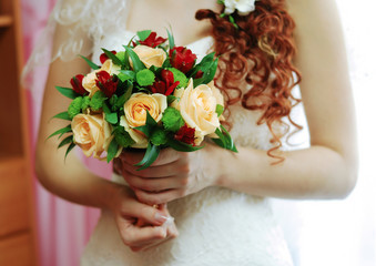 Bright wedding bouquet for the bride with orange roses and red Alstroemeria in the hands of the bride