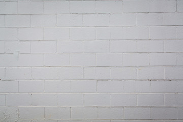 White painted cement concrete block wall with varying shades of white, off white and gray