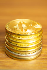 Row of cryptocurrency coins on wooden table, vertical orientation image with selective focus for finance and business concept.
