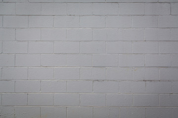 Dingy gray Rough textured painted cement concrete block wall with varying shades of white, off...