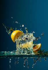 Cocktail gin-tonic with lemon and rosemary on a glass table.