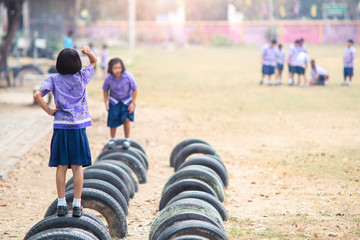 Two little child girl uniform students play rock-paper-scissors on the decorate tyres