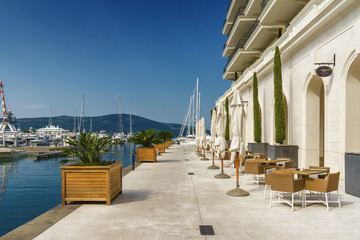 Beautiful and cozy street cafe on the background of luxury yachts at the port of Tivat, Montenegro.