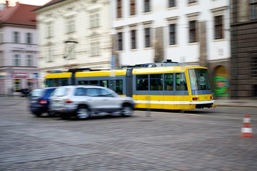 Yellow tram going quickly down the street in motion