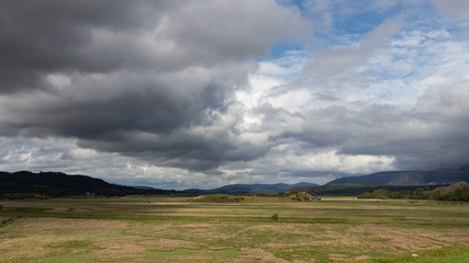 A wide scottish valley shadowed by a sky of angry clouds