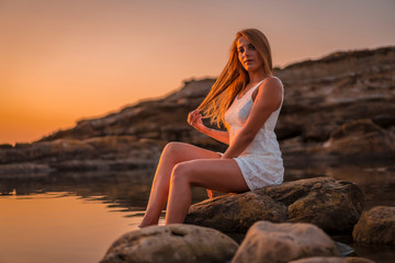 Lifestyle, a young blonde sitting in a white dress on the coast of Basque Country