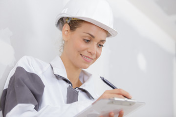 female builder writing on a clipboard