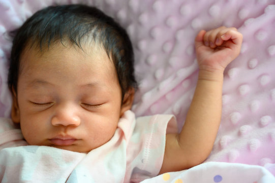 Close up new born asian baby sleep or nap on the pink blanket. Happy family and babu concept background.