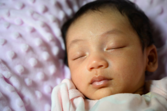 Close up new born asian baby sleep or nap on the pink blanket. Happy family and babu concept background.