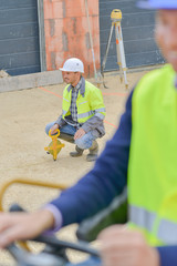 workers examining digger at construction site