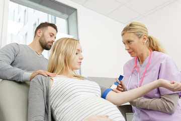 female obstetrician doctor measuring blood sugar of the pregnant woman