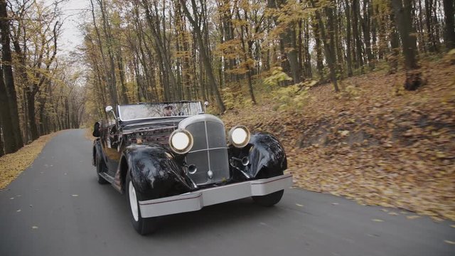 View of retro cabriolet riding at autumn forest