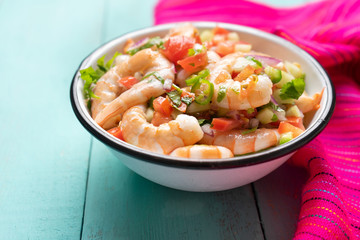 Mexican shrimp ceviche with tomato and serrano pepper on turquoise background