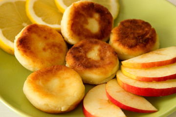 Naklejka na ściany i meble Cheesecakes with lemon and apple on a plate. Close-up.
