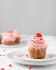 Cupcake with pink buttercream and pomegranate seeds