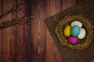 Easter eggs and pussy willow on wooden background. Natural colored eggs in a easter nest. Flat lay photography with space for text. Top view.