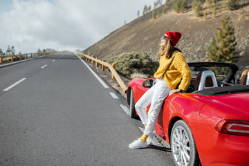 Lifestyle portrait of a carefree woman dressed casually in yellow sweater and red hat standing near...