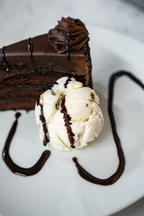 slice of fudge cake and vanilla ice cream with chocolate syrup drizzled on top - 323047795