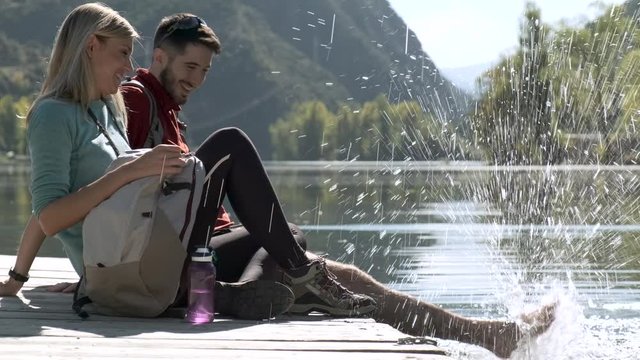 Video of two travel hikers in love enjoying the nature while playing with water in the lake of the mountain.