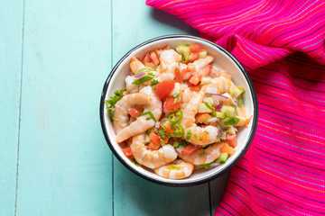Mexican shrimp ceviche with tomato and serrano pepper on turquoise background
