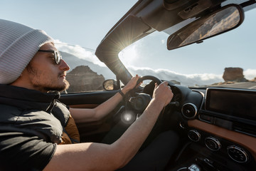 Man driving convertible car while traveling on the desert road. Carefree lifestyle and travel...