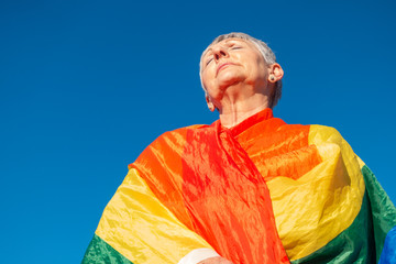 Caucasian older woman with LGBT flag on blue background